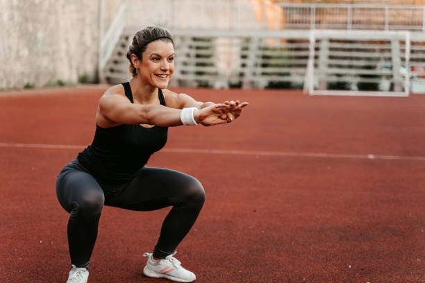 woman doing squats on a running track